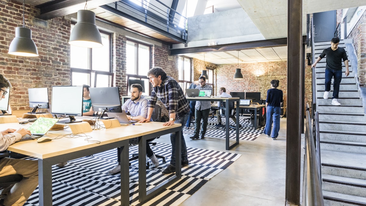 Coworking-Raum mit hohen Fenstern, mehreren Menschen am Laptop — Symbolbild zu einem Beitrag.