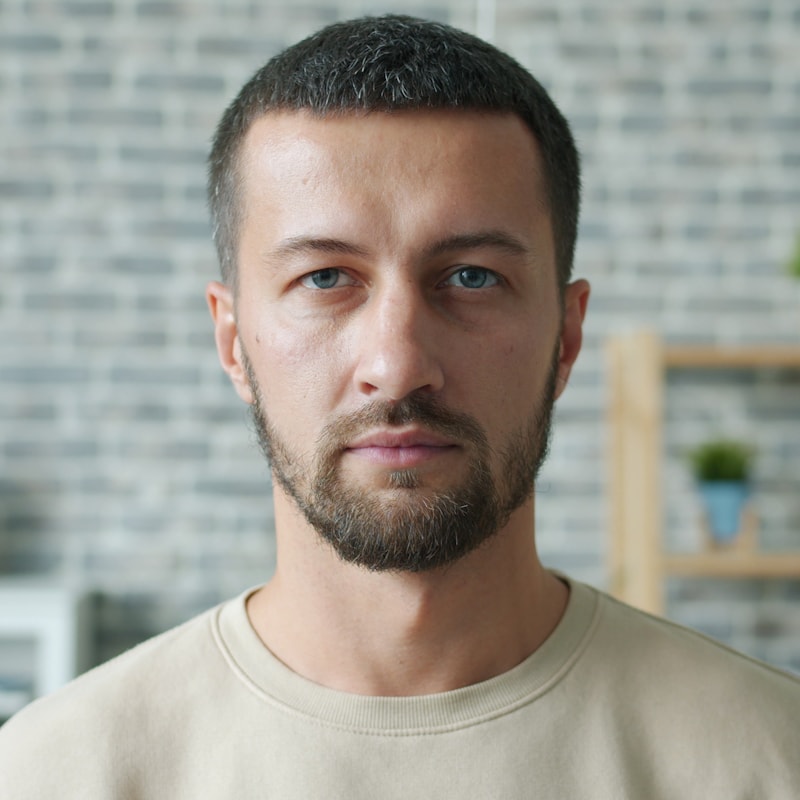 Symbolbild: Mann mit kurzem Bart in beigefarbenem Pullover im hellen Bürohintergrund. Echtes Foto folgt.